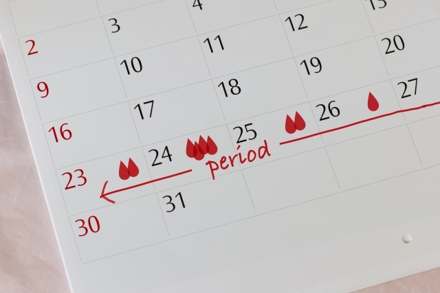 白いカレンダーに赤いペンで書かれた生理周期